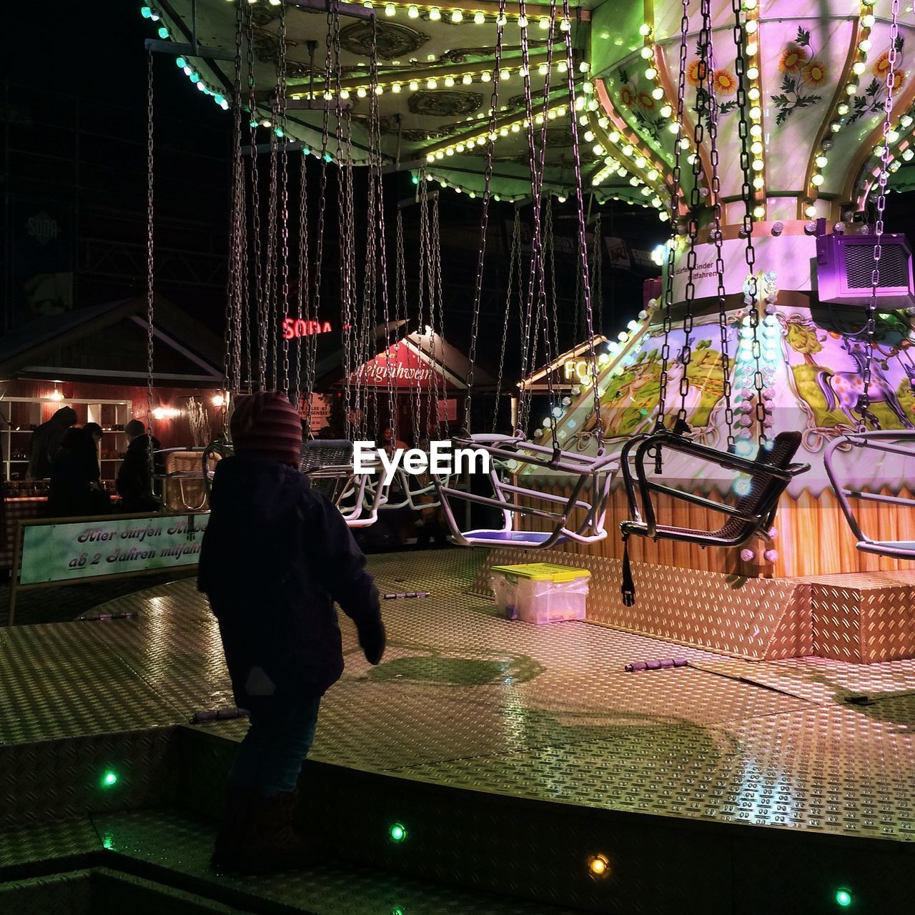 People by illuminated chain swing ride at amusement park