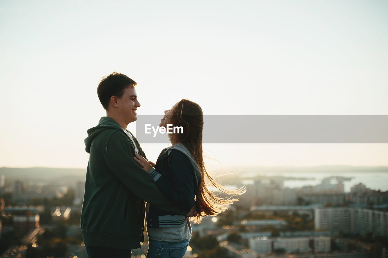 Couple embracing while standing against sky