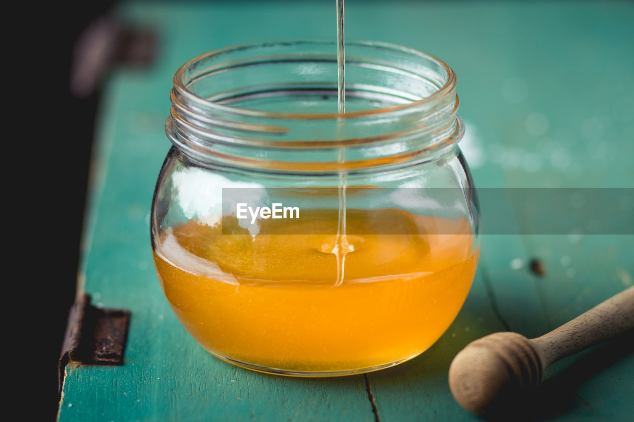 High angle view of honey falling in glass jar on table