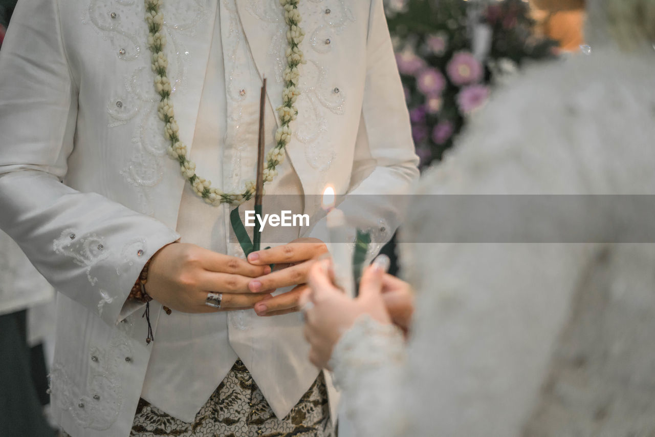 Midsection of bride and groom performing rituals during wedding ceremony