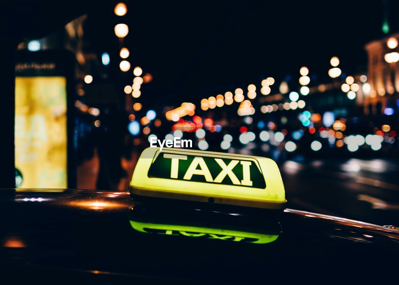 Close-up of illuminated taxi sign on car at night