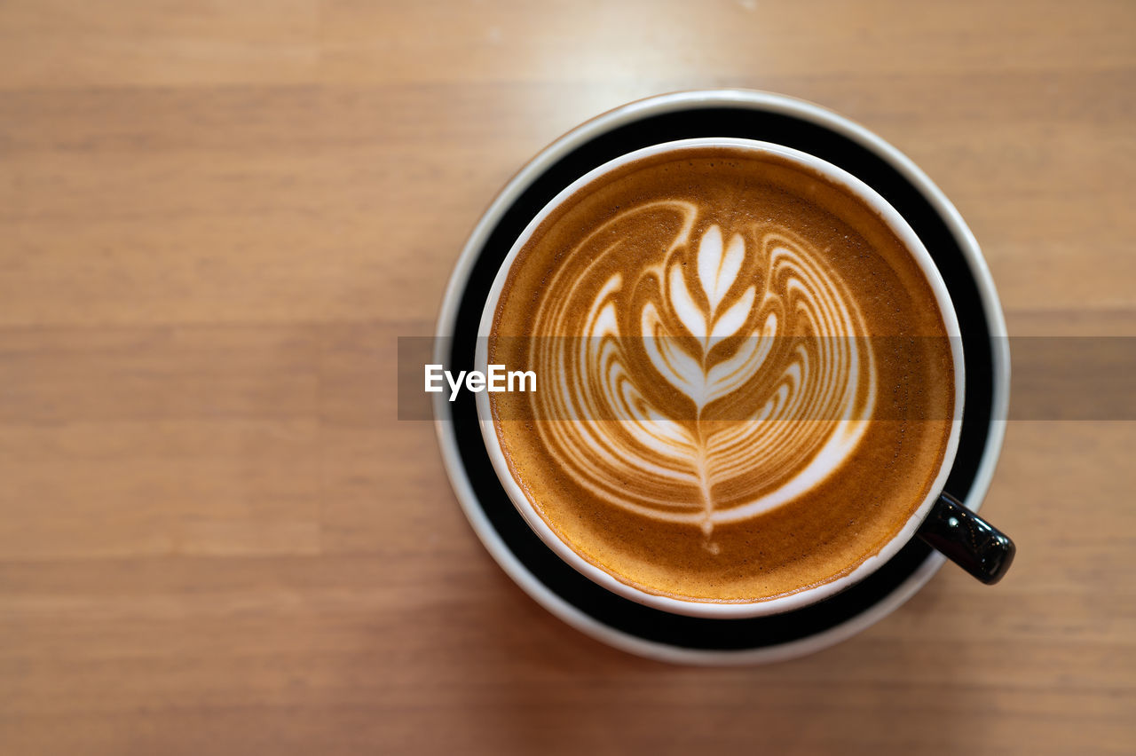 Beautiful of latte art coffee cup on wooden table, flat lay