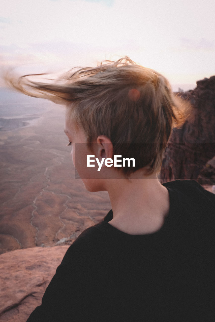 Wind blowing boy's hair over canyonlands viewpoint.