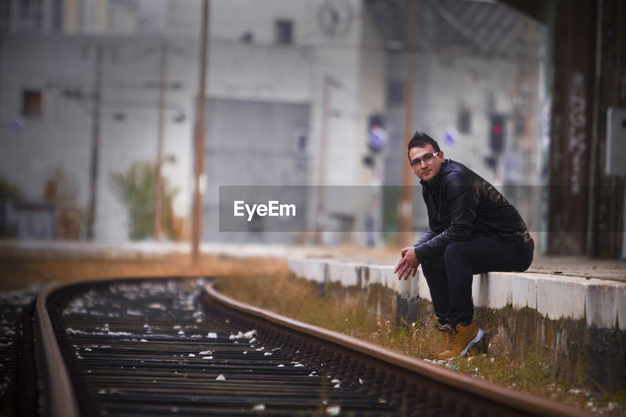 Portrait of man sitting at railroad station platform