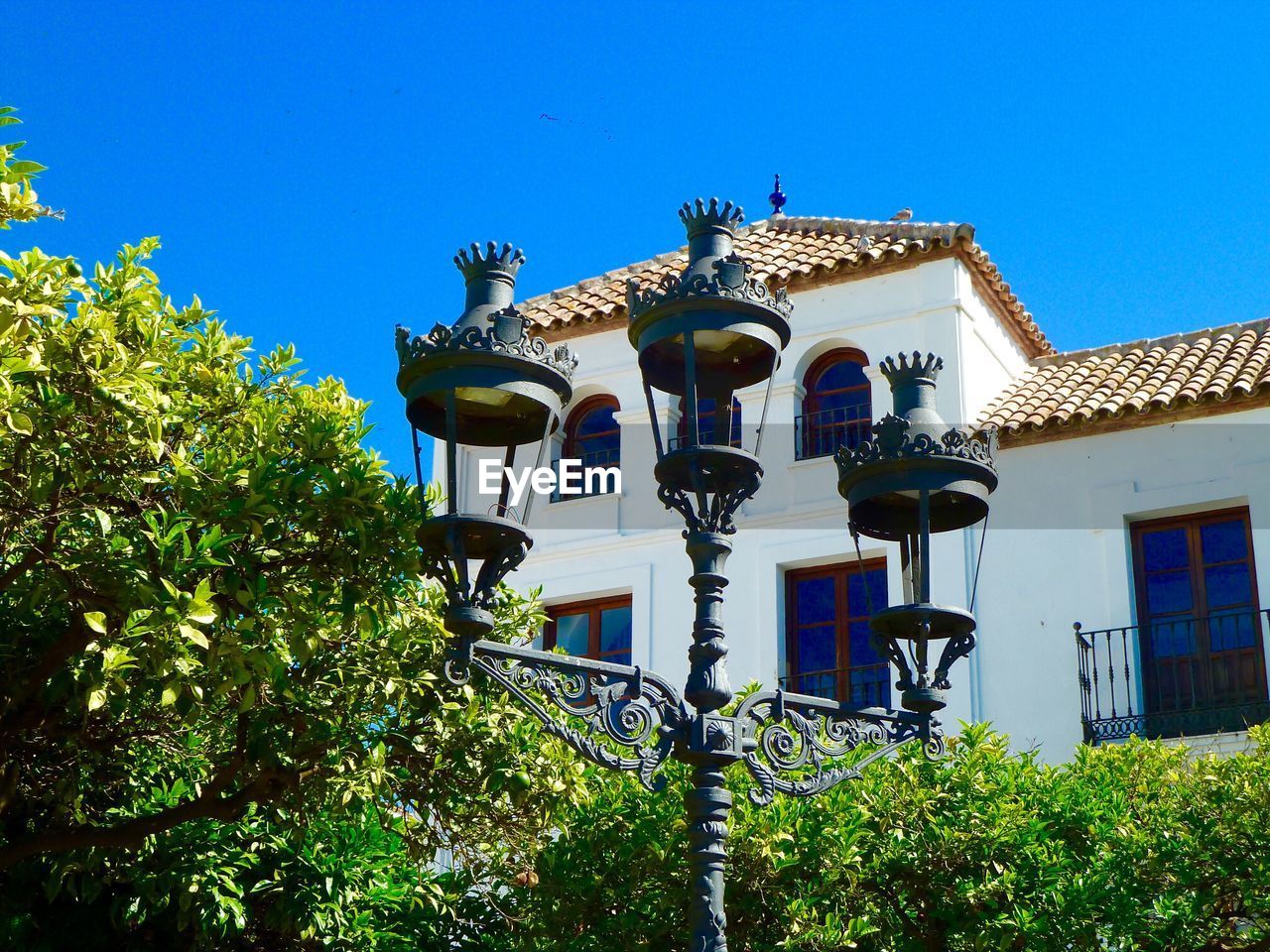 Low angle view of lamp post and house against clear blue sky