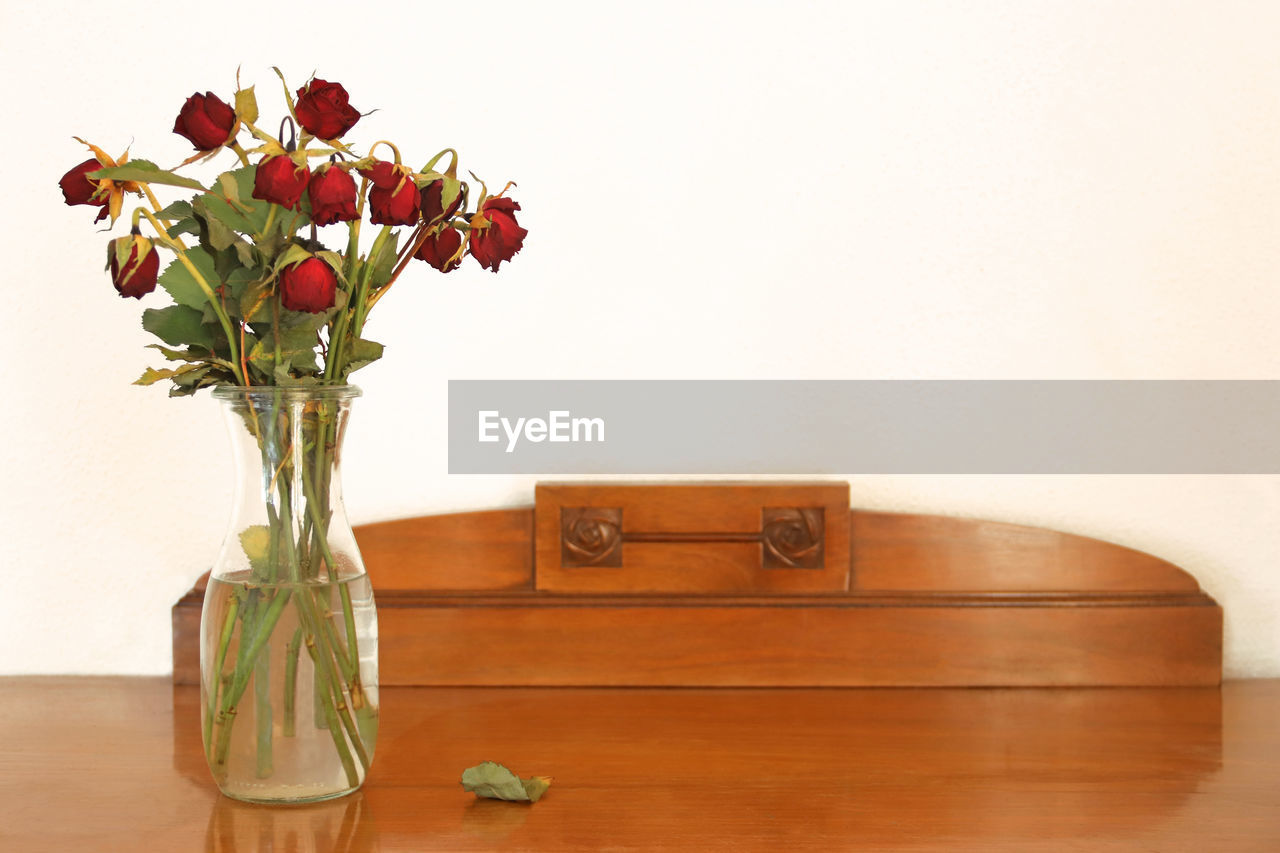 RED ROSE IN VASE ON TABLE