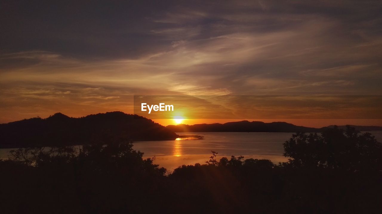 SCENIC VIEW OF LAKE AGAINST SKY AT SUNSET