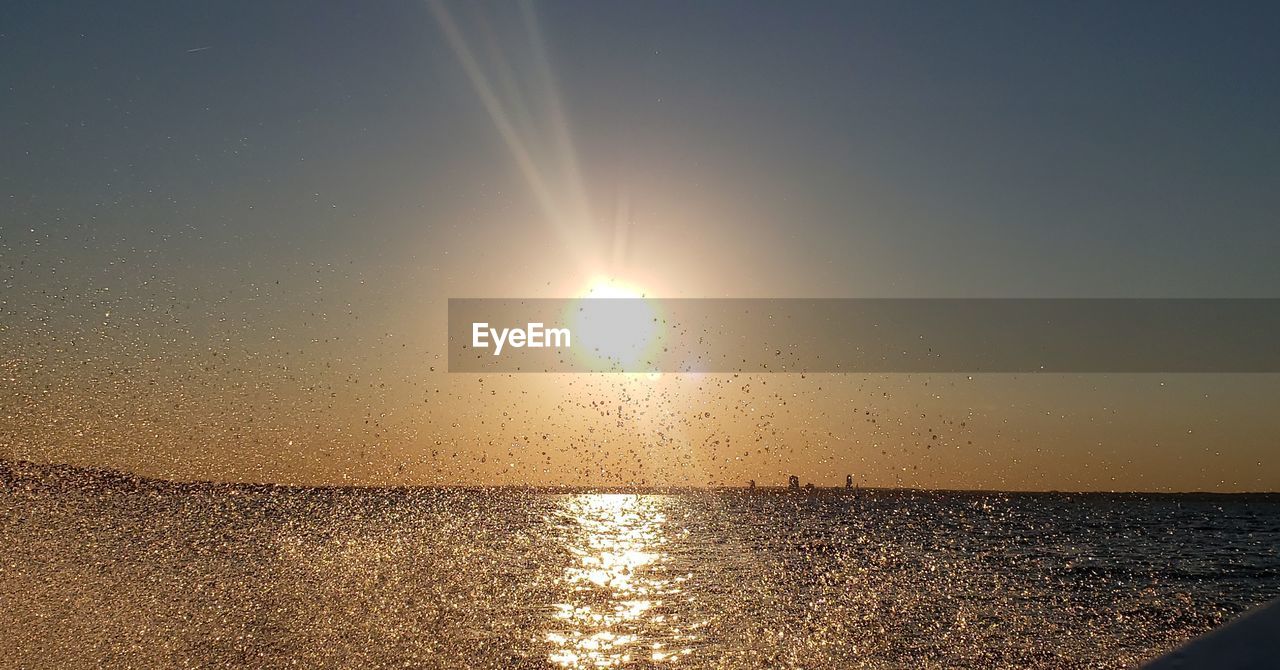 SCENIC VIEW OF SEA AGAINST BRIGHT SUN DURING SUNSET