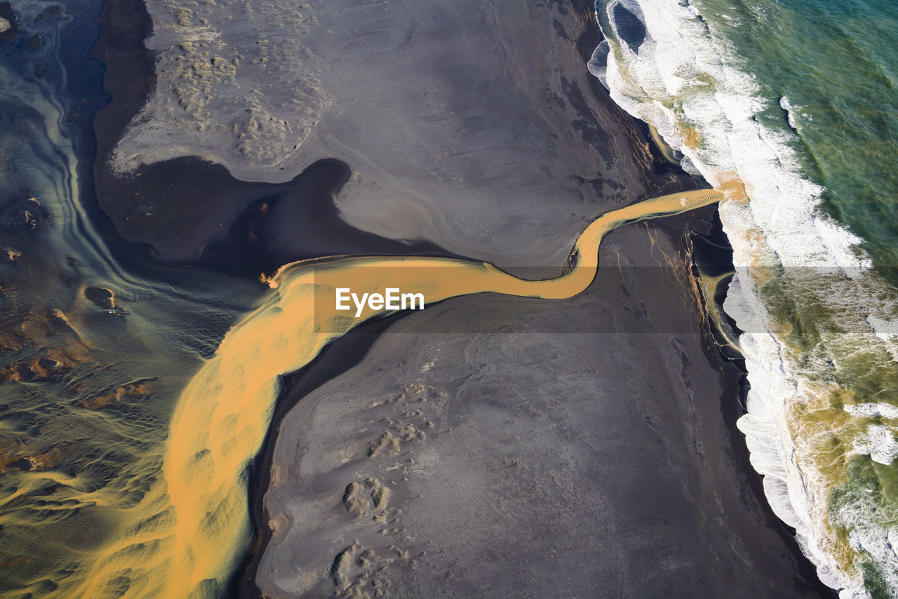 Aerial view of braided orange river flowing into ocean in southe