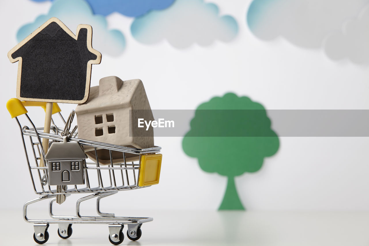 Close-up of model home in miniature shopping cart against white background
