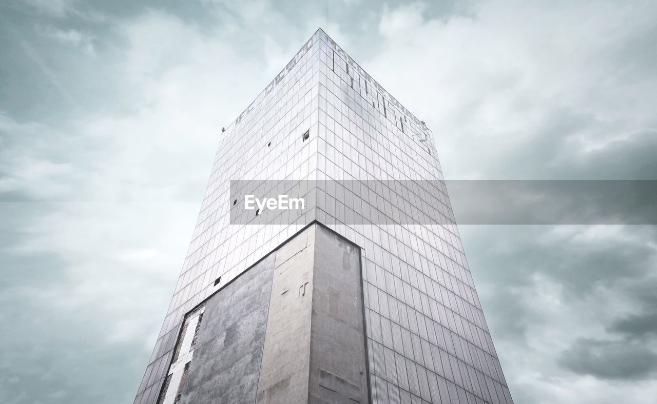 Low angle view of old abandoned building against cloudy sky
