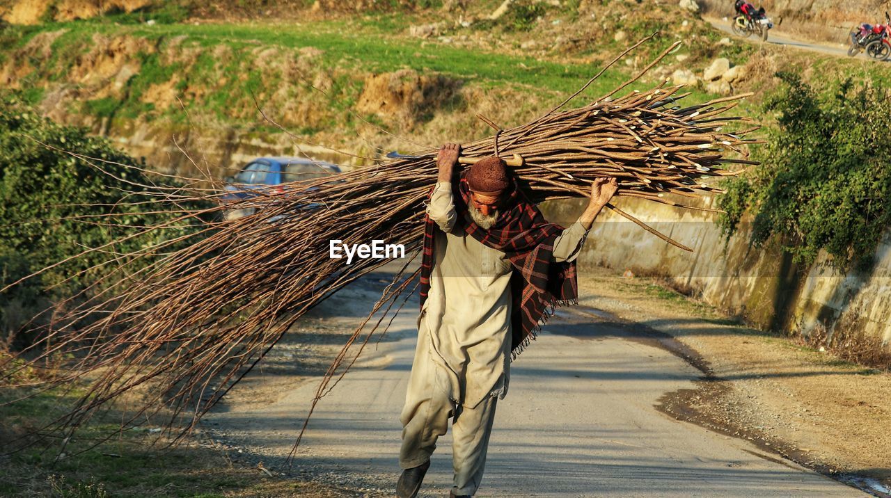 Man walking on footpath by road on field