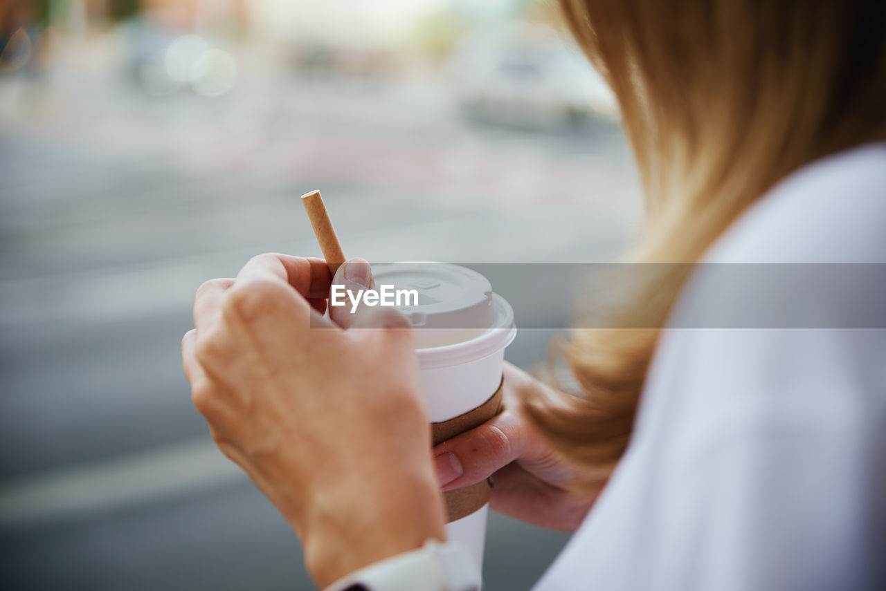 Woman holds paper coffee cup at city street