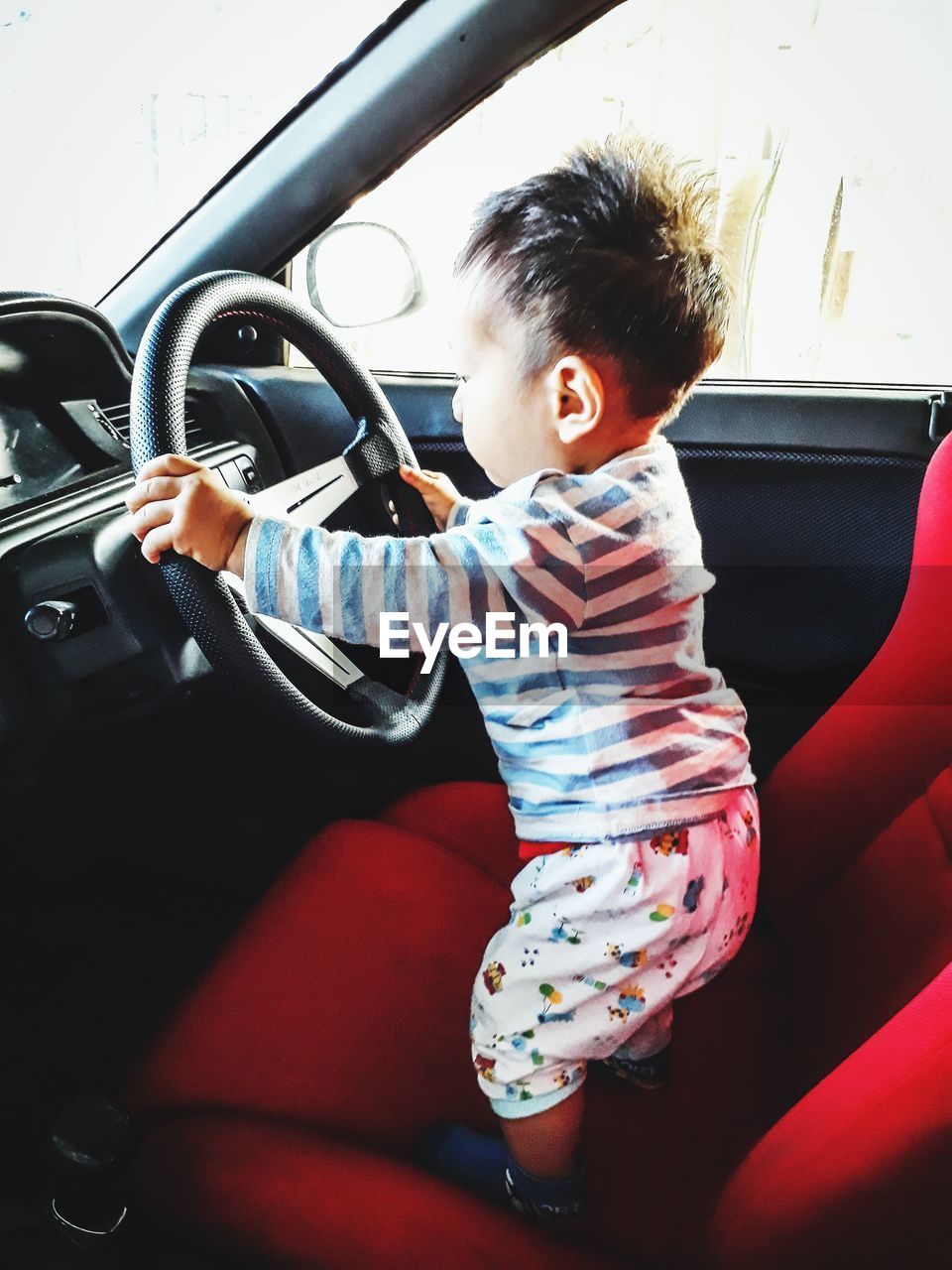 Side view of baby boy playing in car