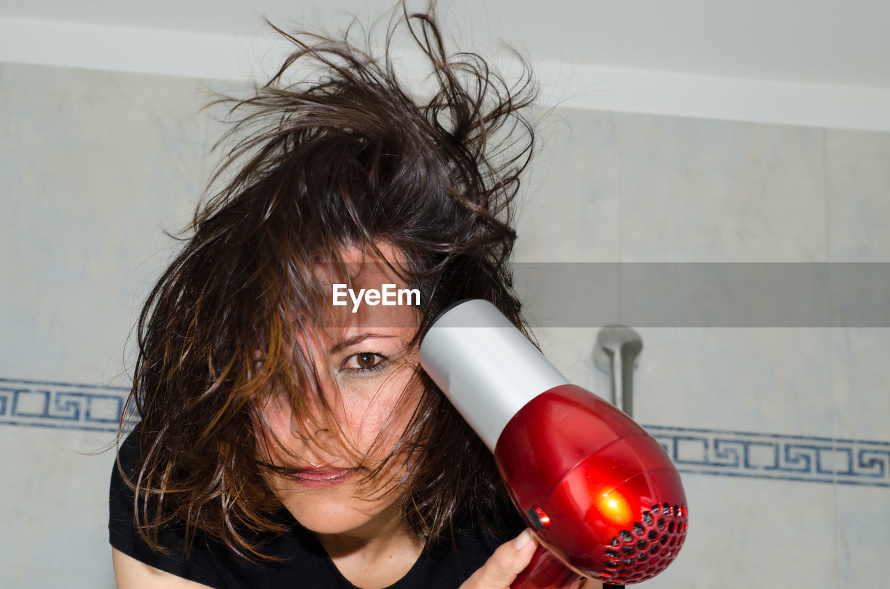 Portrait of woman holding hair dryer