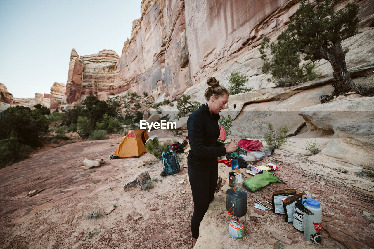 Female hiker prepares dinner while remote camping in the maze utah