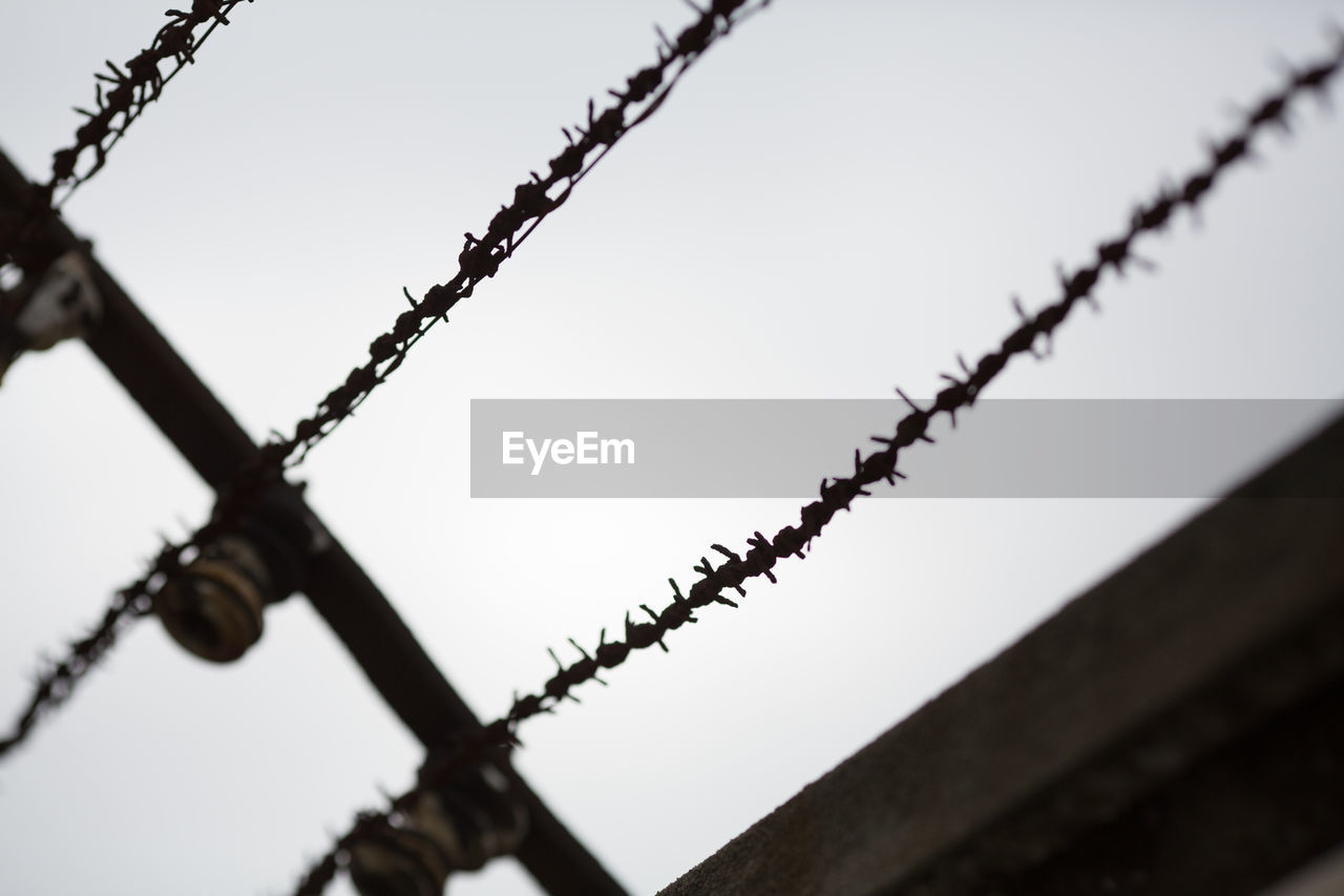 LOW ANGLE VIEW OF BARBED WIRE AGAINST SKY