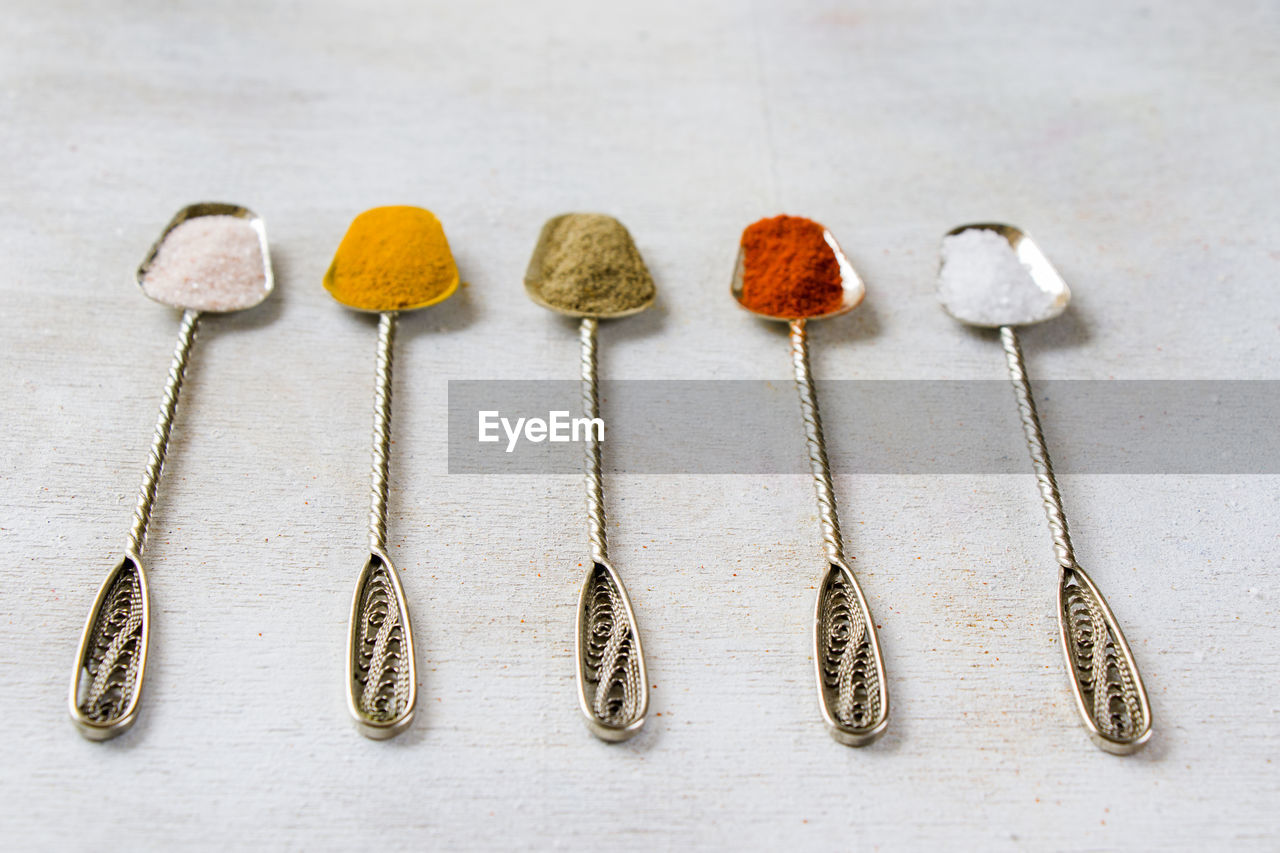 Variation of spices on the vintage silver spoons, all spices on the table, colorful food background