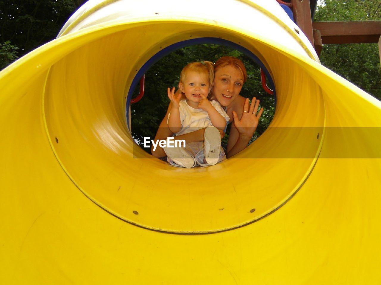 Portrait of happy mother with daughter in slide tunnel