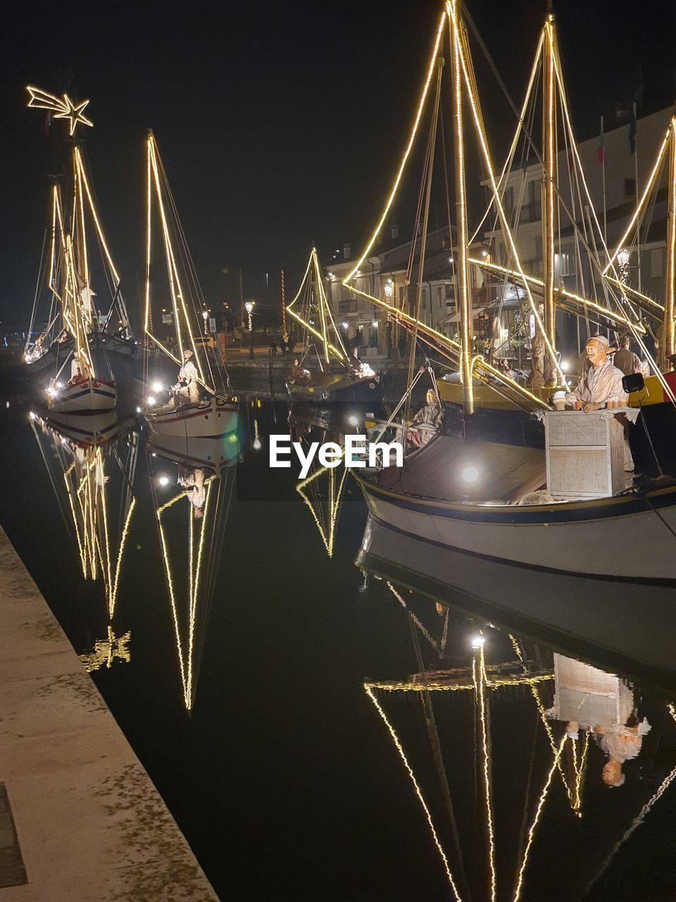 ILLUMINATED SHIP MOORED AT HARBOR