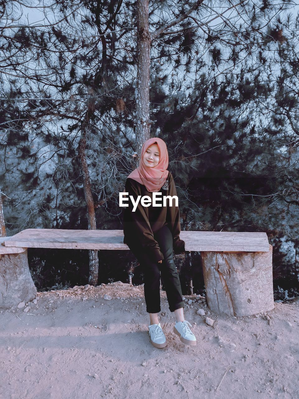 Full length of smiling woman sitting outdoors