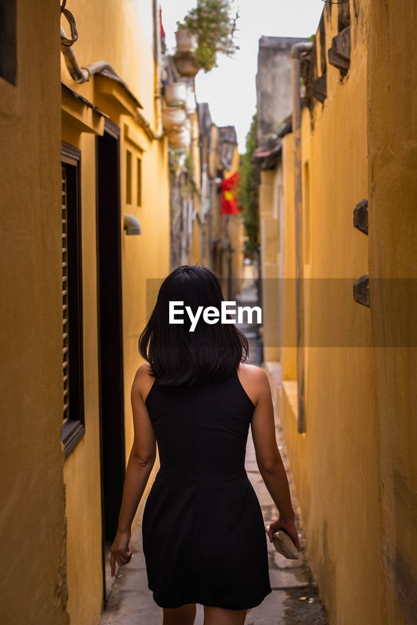 REAR VIEW OF WOMAN IN FRONT OF BUILDING