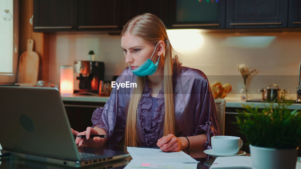 young woman using laptop while sitting on table