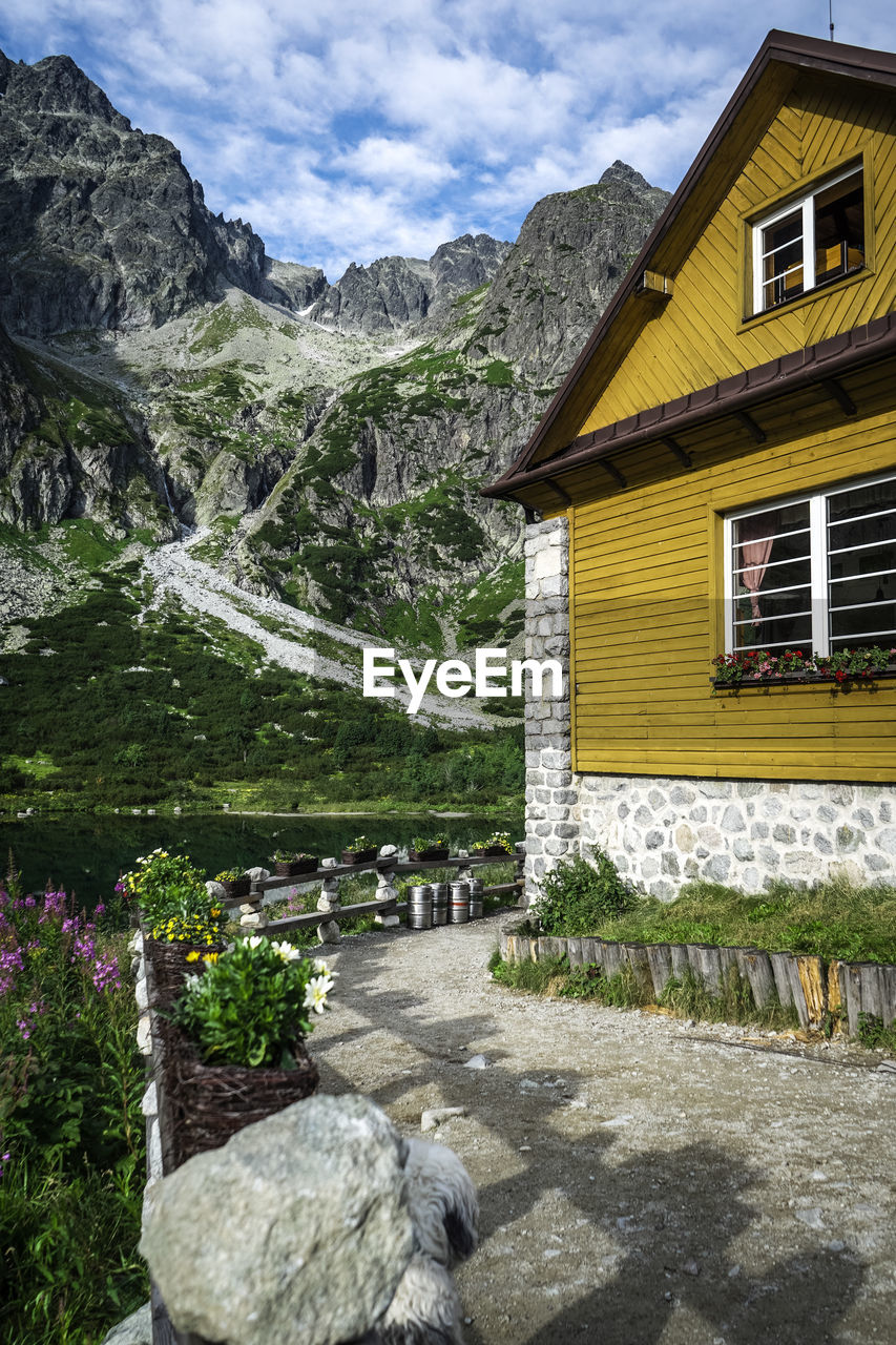 HOUSE AMIDST PLANTS AND BUILDINGS AGAINST MOUNTAINS