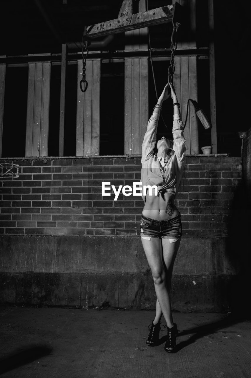 Female model posing against wall at night