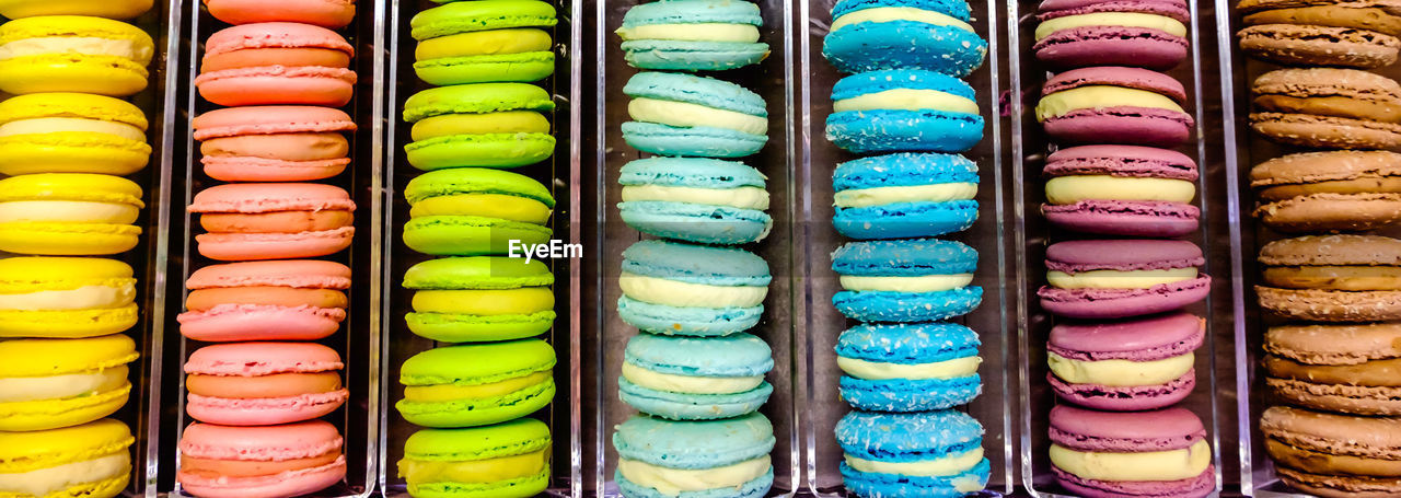 Panoramic shot of macaroons in container for sale at store