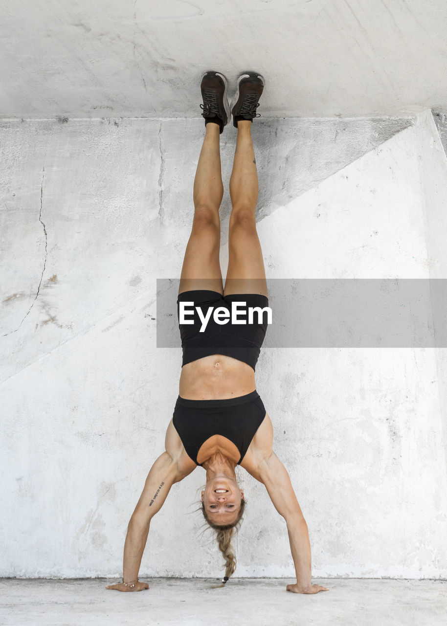 Woman wearing fitness clothes doing handstand