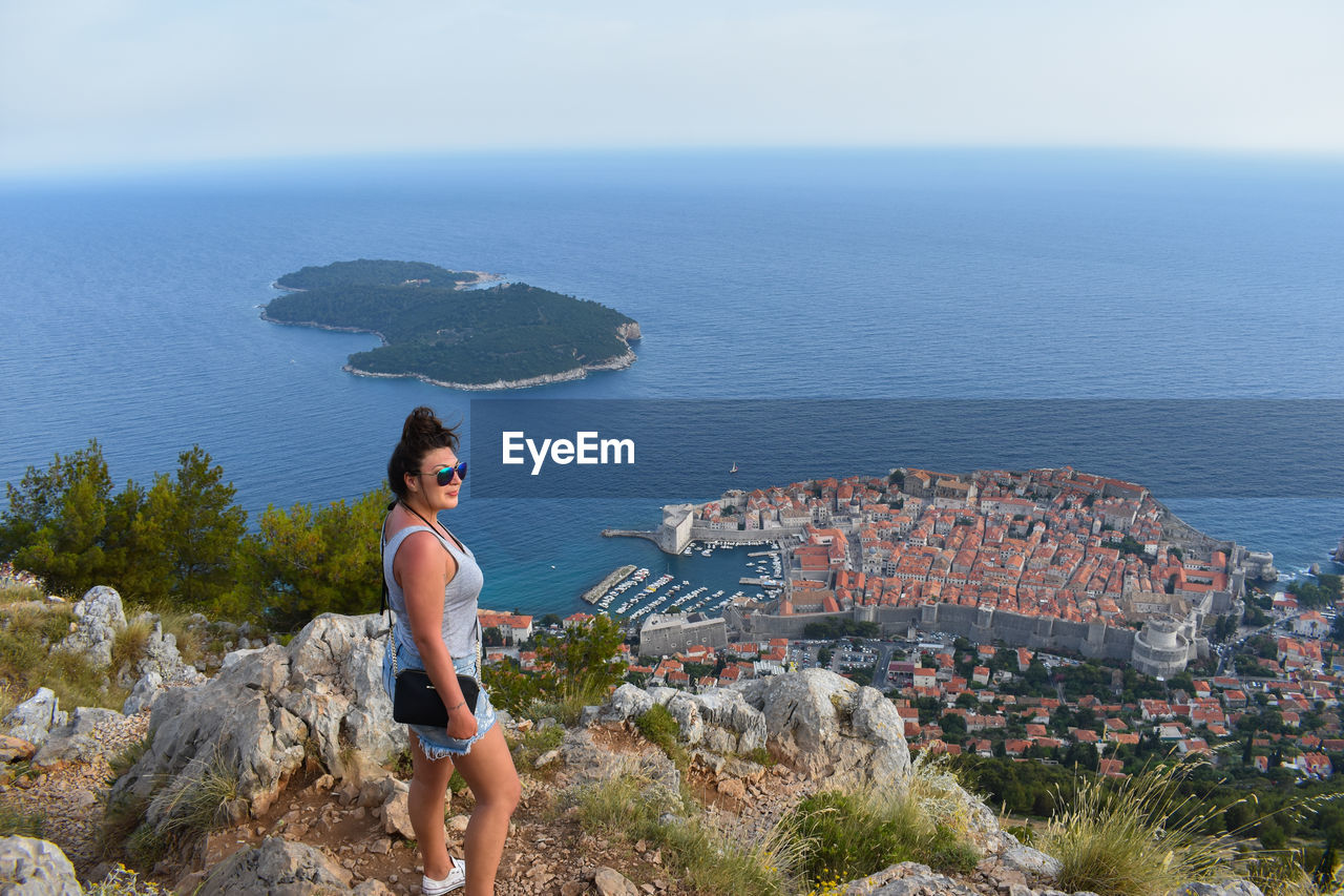 Woman standing on mountain against sea in city