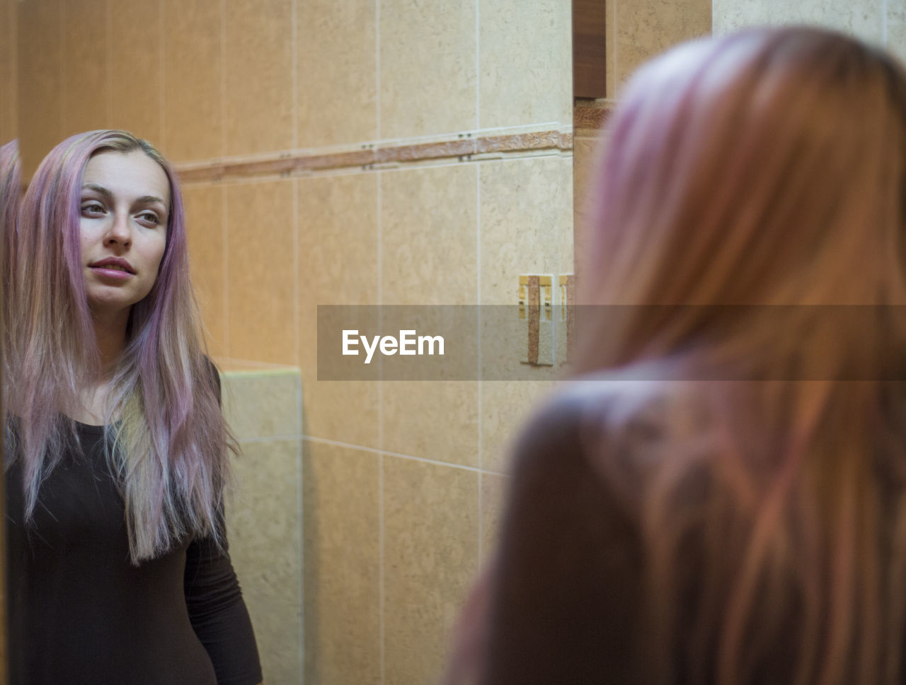 Young woman with long hair reflecting on mirror