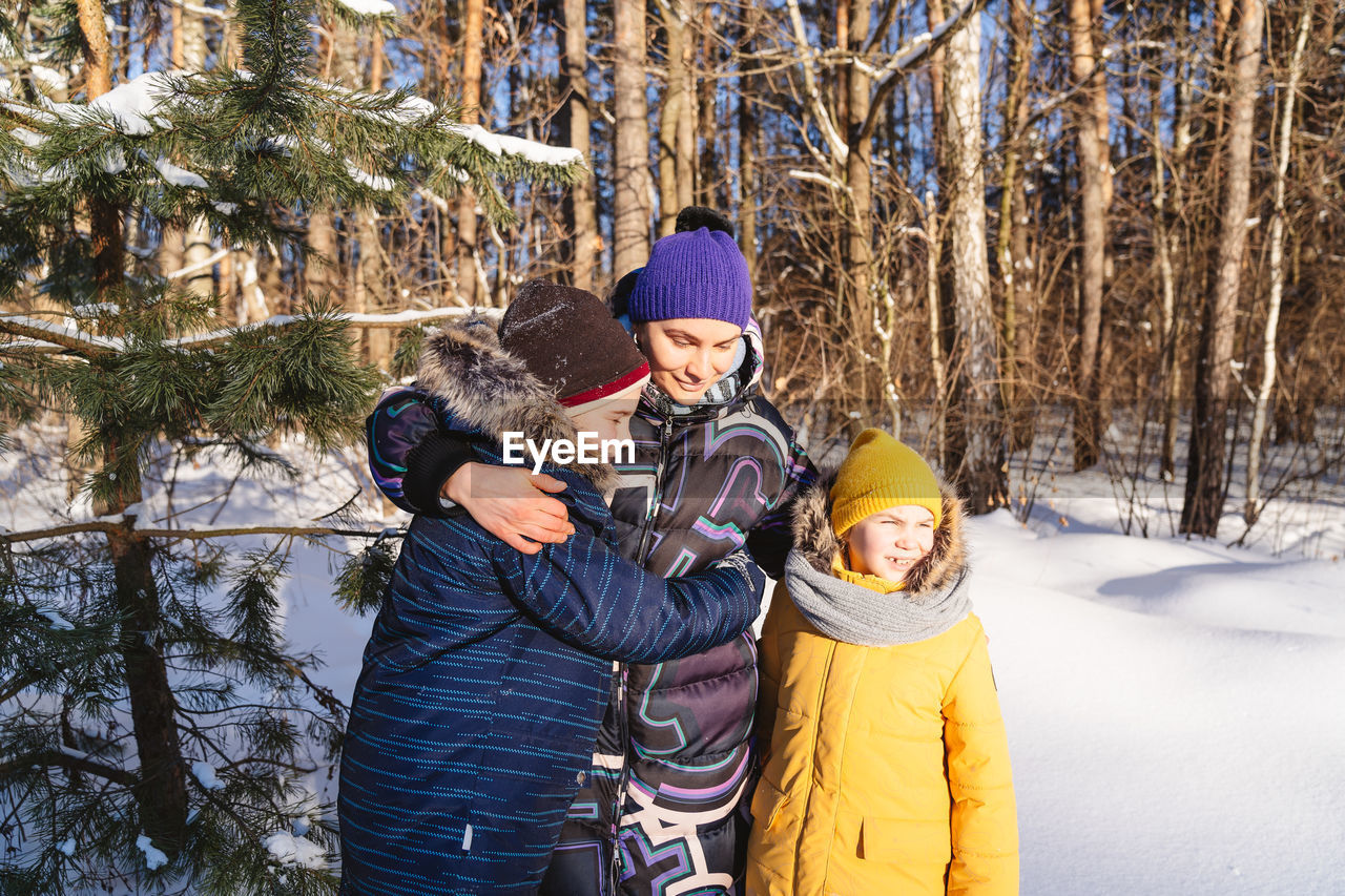 Happy mother and kids standing outdoors during winter