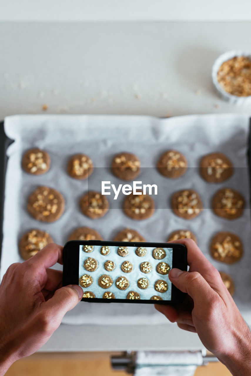 Overhead view of a young man taking a photo of his home-made cookies