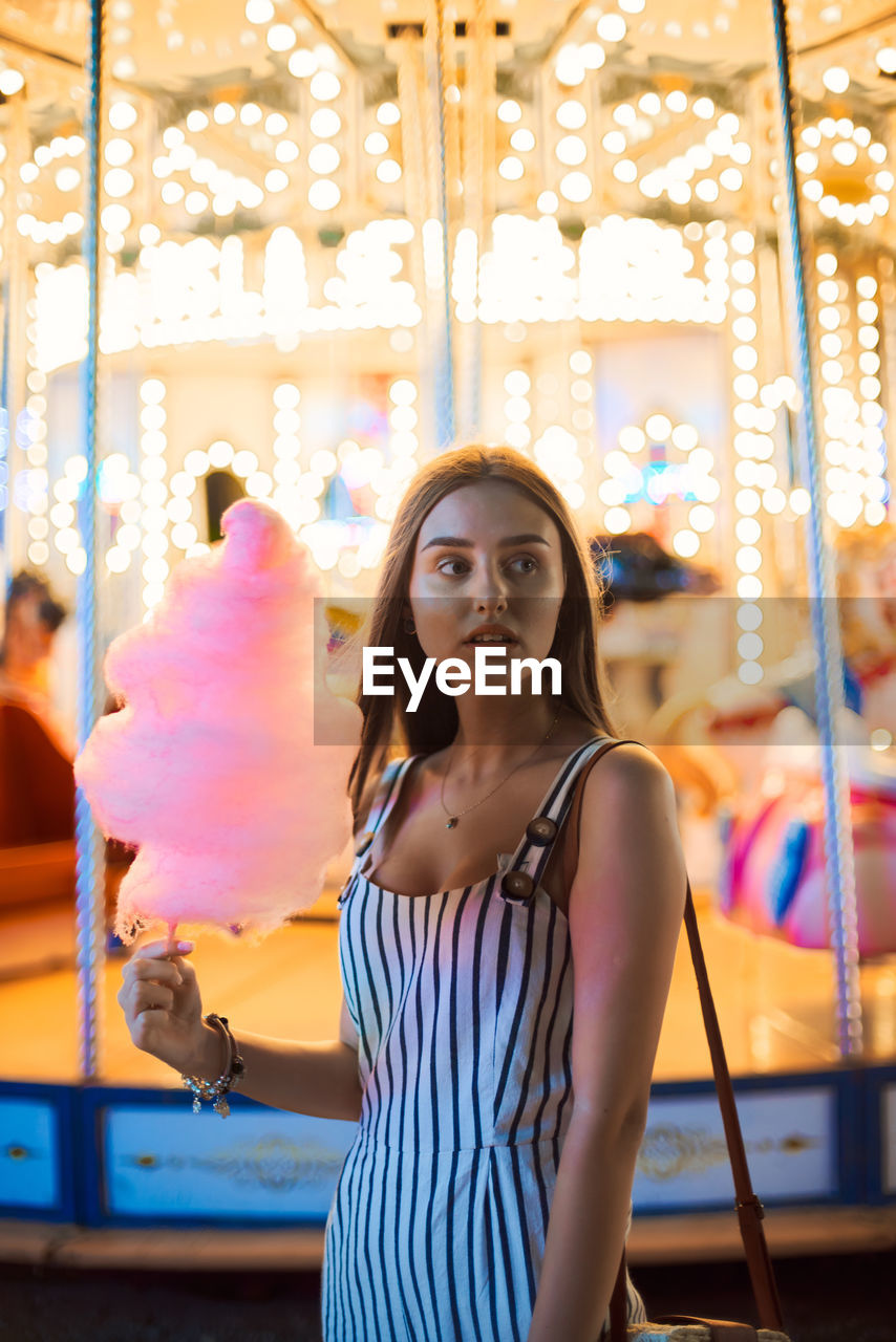 PORTRAIT OF YOUNG WOMAN IN CAROUSEL AT AMUSEMENT PARK