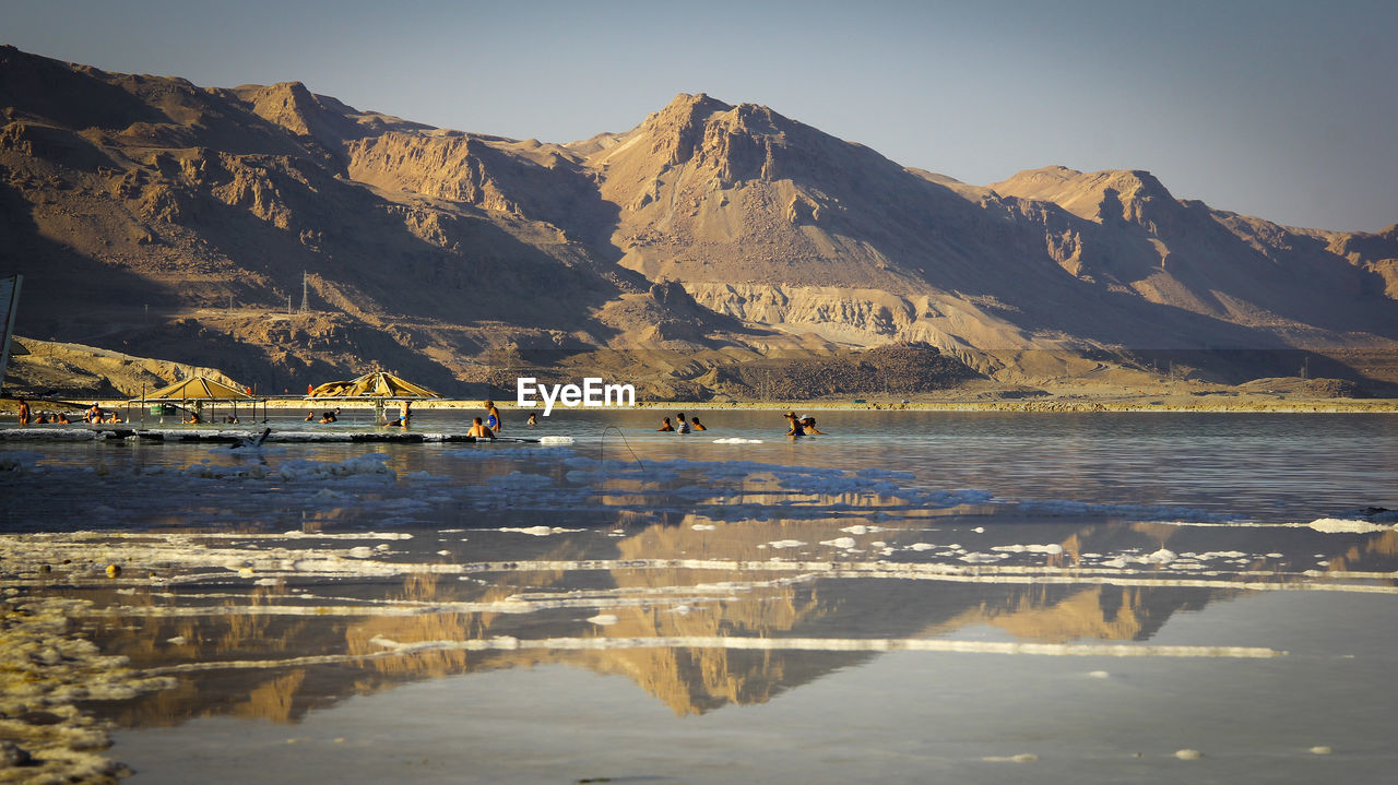 People enjoying in sea against mountain range