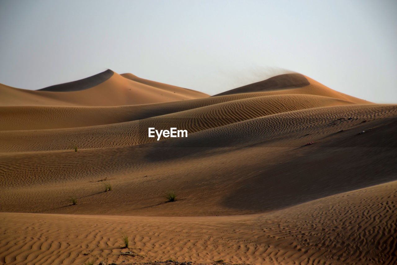 Sand dunes in desert against clear sky