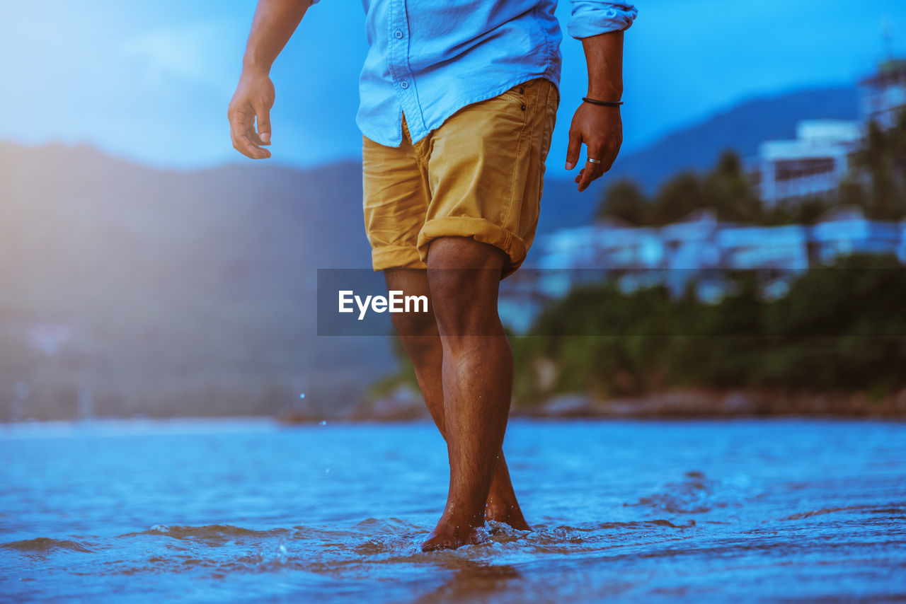 Low section of man standing in sea