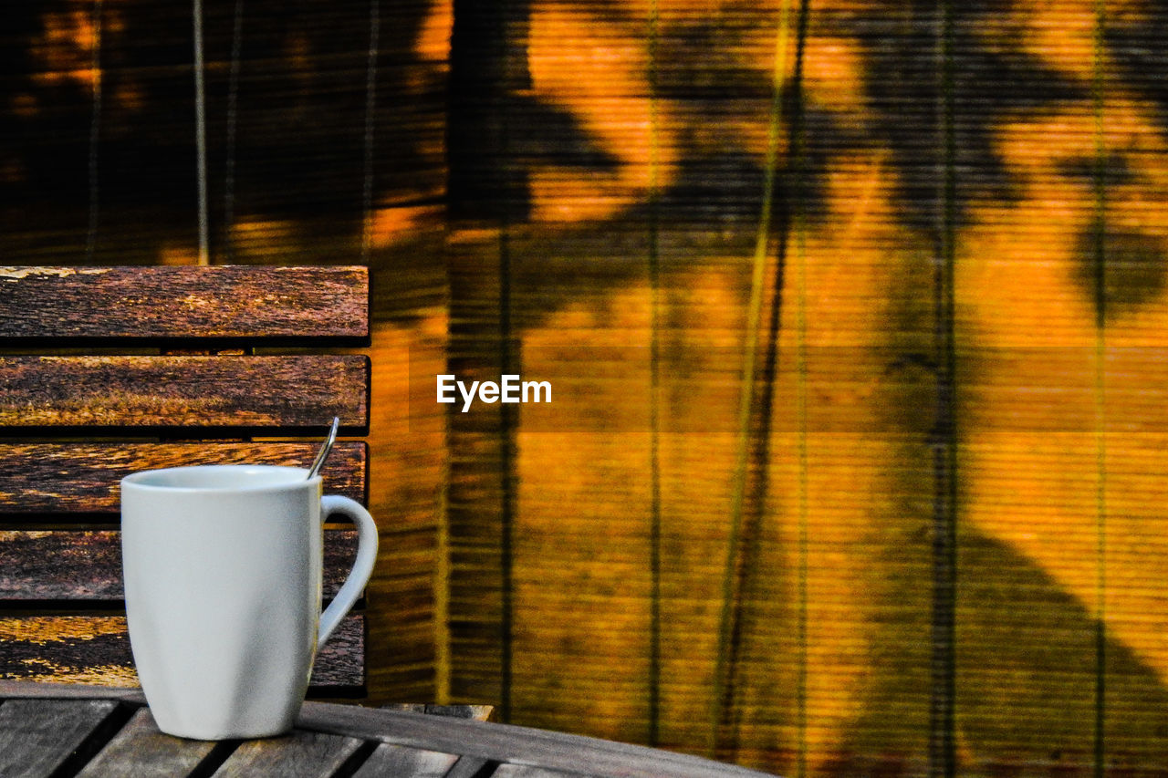 CLOSE-UP OF COFFEE CUP ON TABLE AGAINST BLURRED BACKGROUND