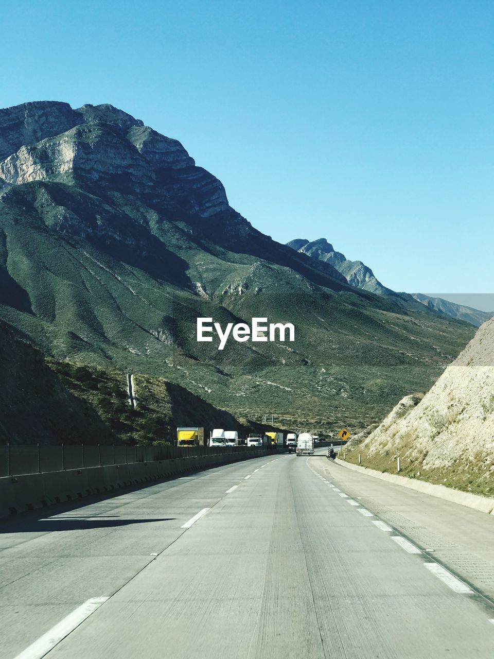 ROAD LEADING TOWARDS MOUNTAINS AGAINST CLEAR SKY