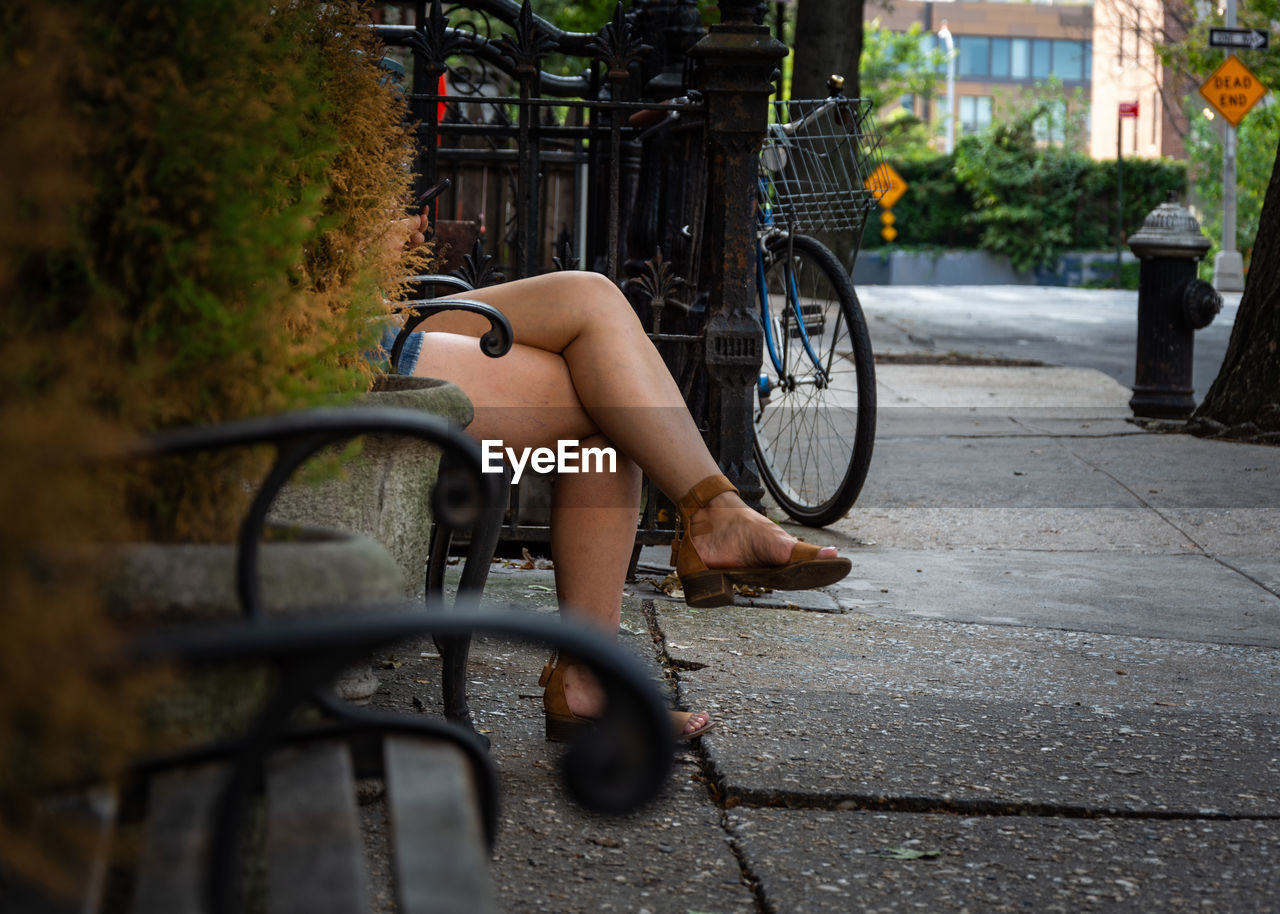 Women seat on bench street in city