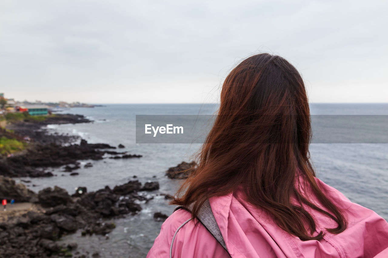 Rear view of woman looking at sea against sky