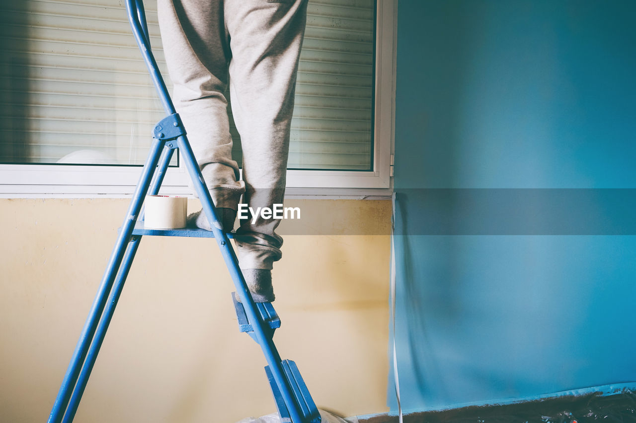 Low section of man standing in front of ladder