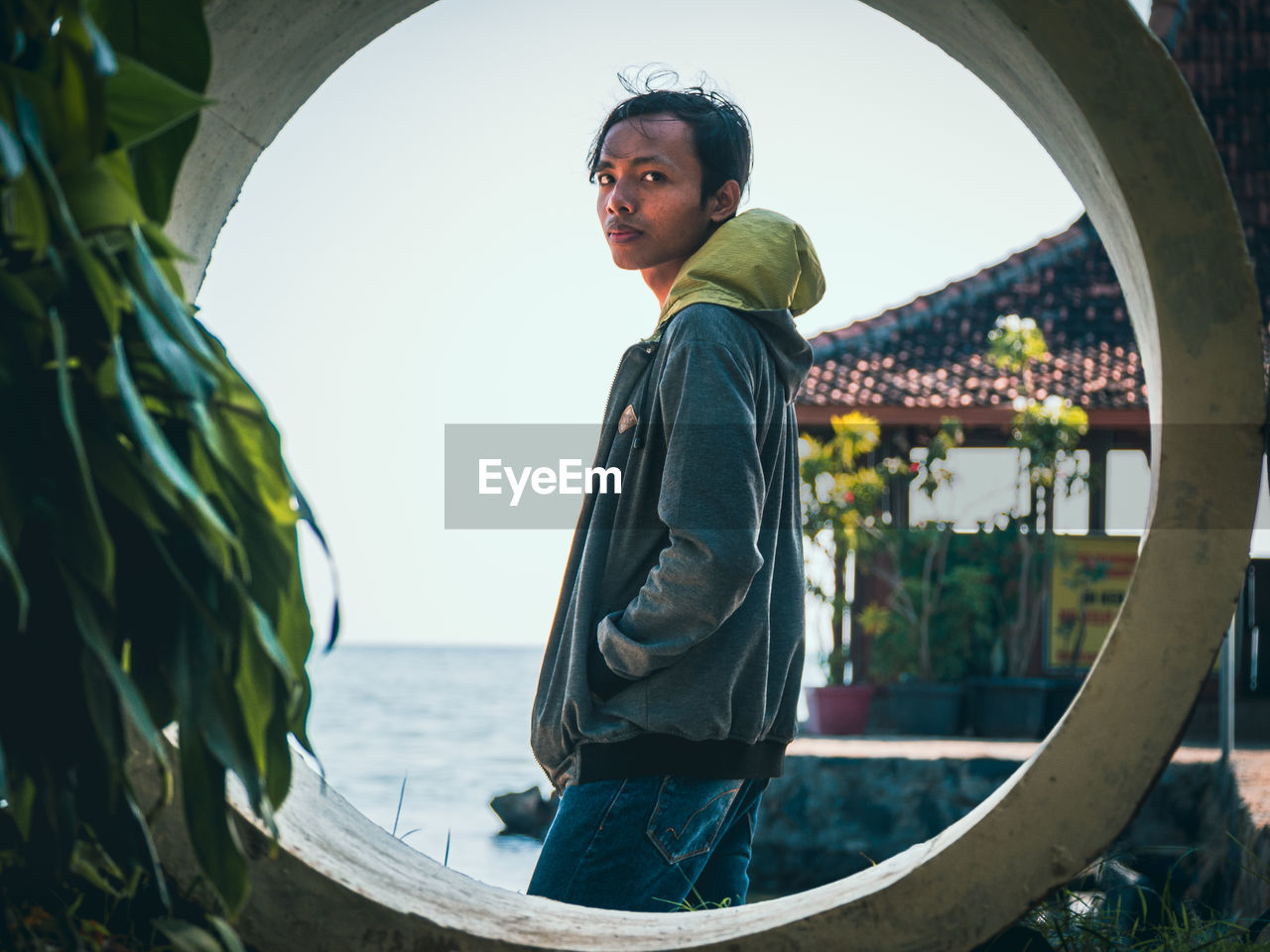 A stylish man in the center of a circle on a house and sea background