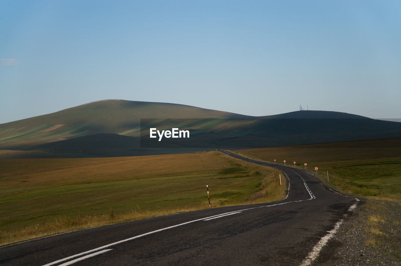 SCENIC VIEW OF ROAD BY MOUNTAINS AGAINST CLEAR SKY