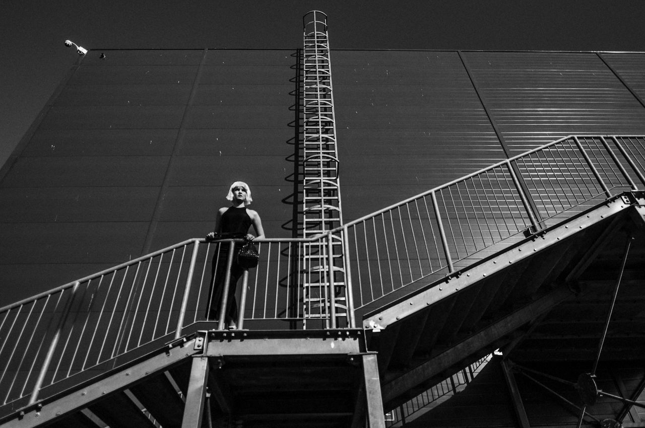 FULL LENGTH OF YOUNG WOMAN STANDING ON WALL