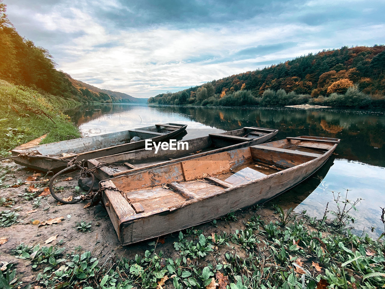 Old wooden boats on river bank under cloudy sky. incredible natural landscape with river and forest