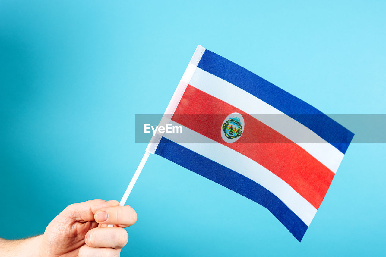 flag, hand, blue, patriotism, holding, one person, symbol, studio shot, colored background, adult, copy space, emotion