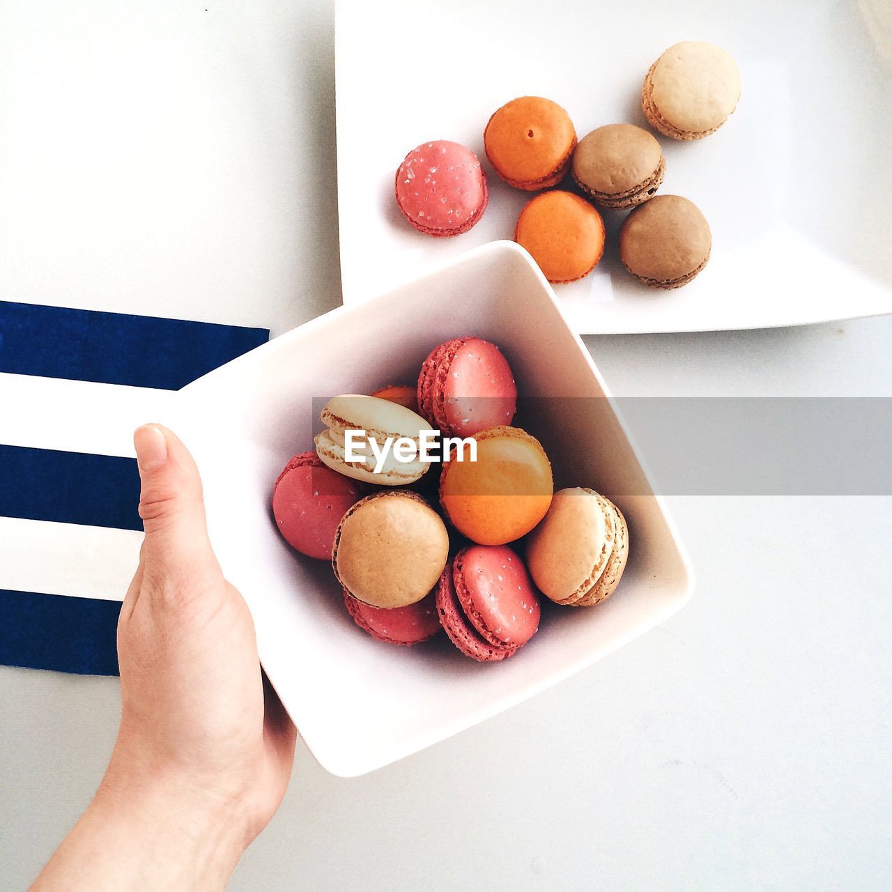 Cropped hand of person holding macaroon bowl